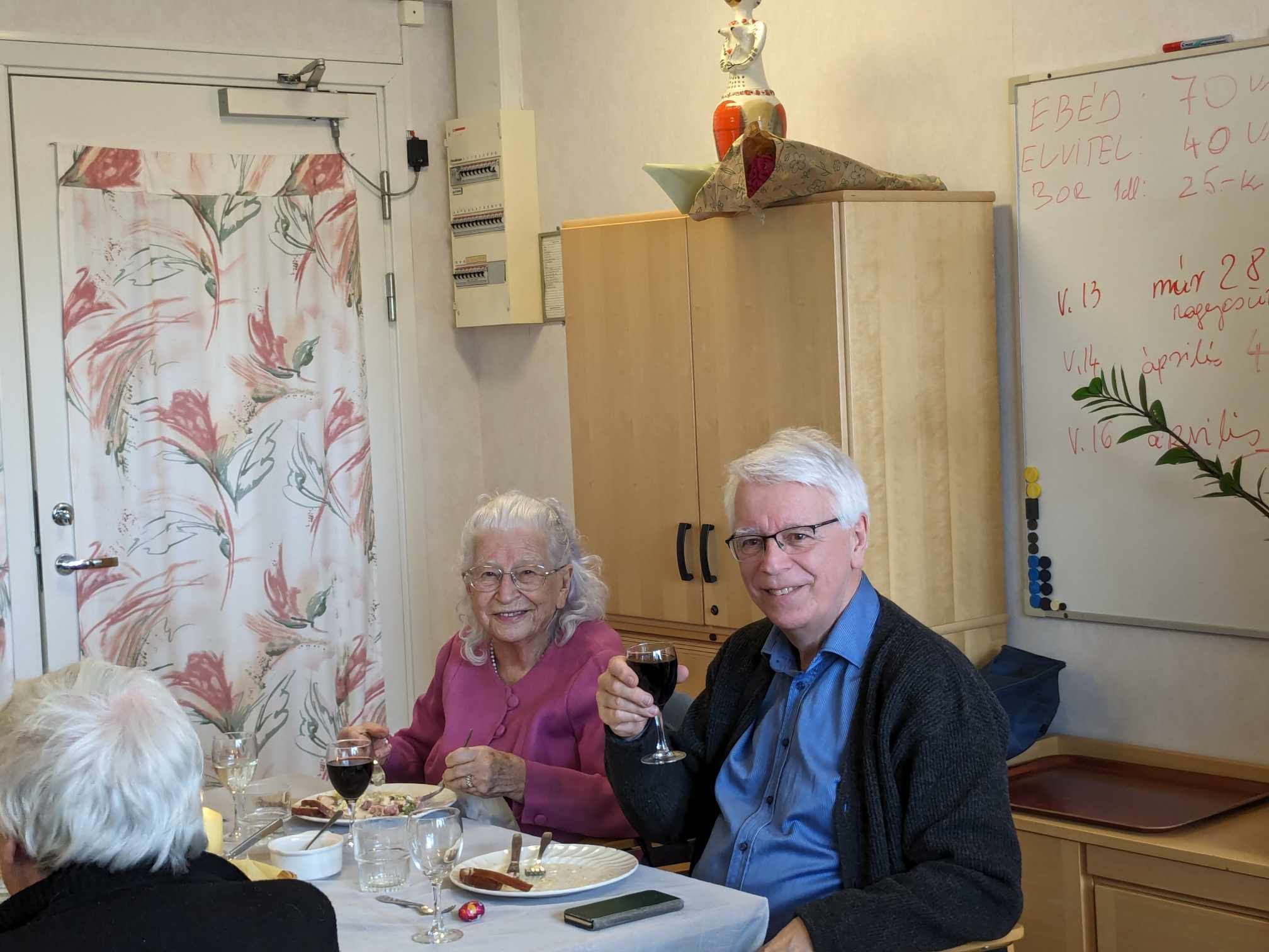 Två boende skålar i rödvin vid lunchbordet