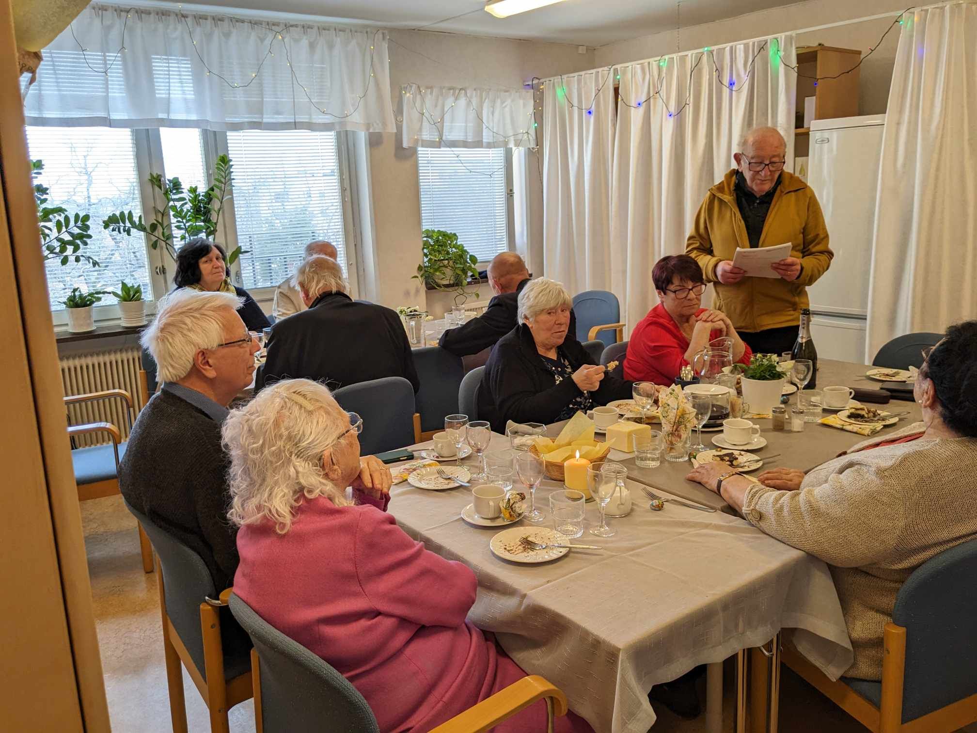 En boende läser upp ett tal för gästerna vid kaffebordet