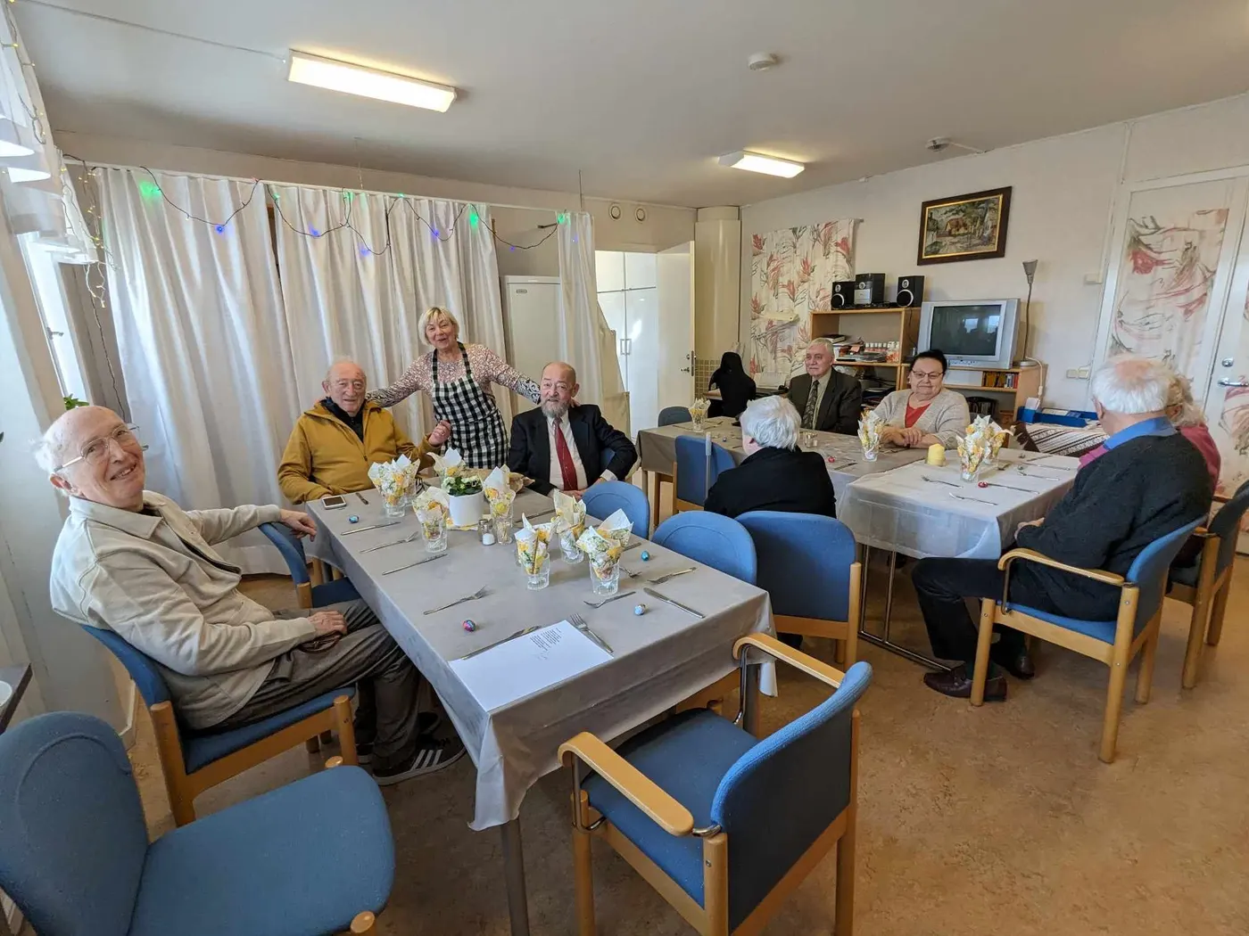 Boende samlade kring påskdukade bord i Pannonia Hems sällskapsrum