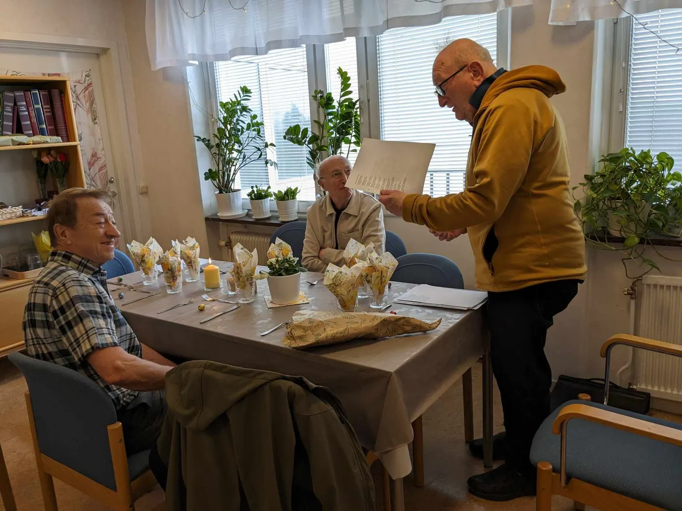 En boende läser upp en text för sina bordsgrannar